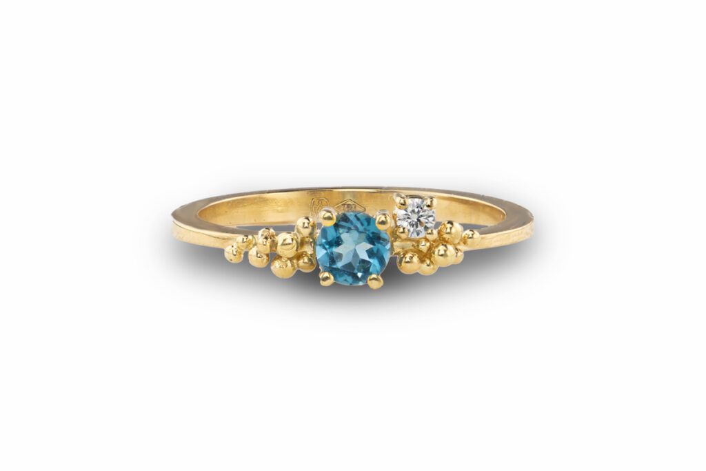 Geelgouden ring in 18kt, frivool modelletje gezet met een diamantje en een blauwe topaas.
