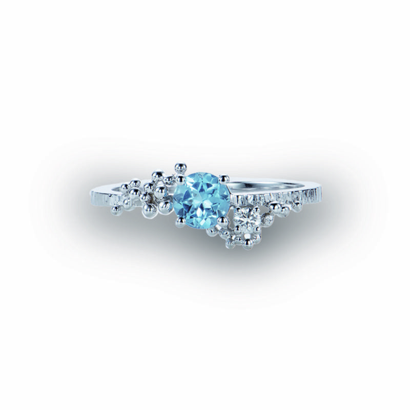 Deze witgouden ring in 18 kt is gezet met een centrale blauwe topaas en versierd met diamant en gouden bolletjes.